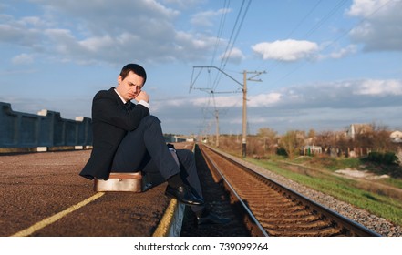 Depressed young man sitting on suitcase head in hands on the railway platform alone, Cry, drama concept, sad businessman.