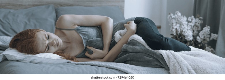 Depressed Young Pregnant Woman Lying On Bed Crying Considering Abortion