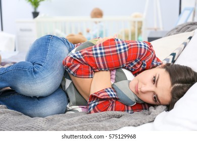 Depressed Young Woman Lying On Bed At Home