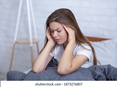 Depressed young woman massaging her temples to ease headache or stress in bed. Millennial lady suffering from sleep deprivation, mental disorder, overwhelmed with negative thoughts - Shutterstock ID 1873276807