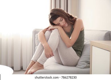 Depressed young woman sitting on couch at home - Shutterstock ID 786278230