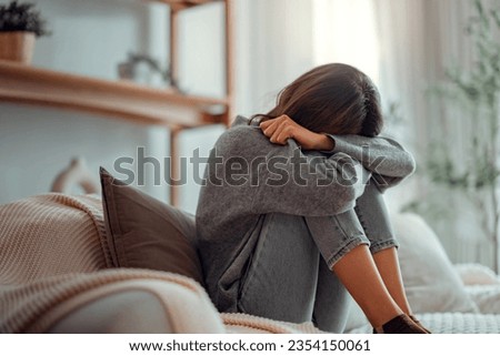 Depressed young woman sitting on couch in the living room at home, Frustrated confused female feels unhappy problem in personal life quarrel break up with boyfriend.