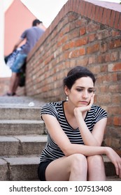 Depressed young woman sitting in an urban area
