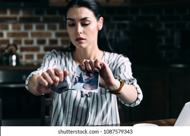 Depressed Young Woman Tearing Photo Of Ex-boyfriend