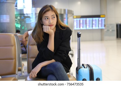 Depressed Young Woman Waiting For The Flight At The International Airport. Portrait Of Thoughtful Beautiful Businesswoman With Baggage Waiting For The Plane Because Of Flight Delay.