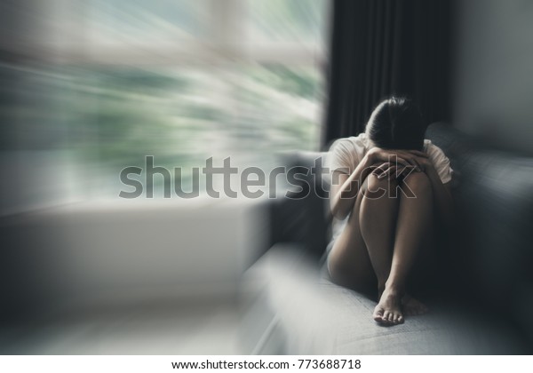 Depression and anxiety concept\
of woman in fetal position on the sofa with gloomy colors. Copy\
space.