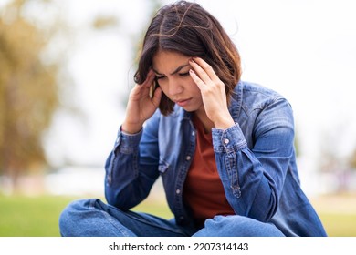 Depression Concept. Portrait Of Upset Young Arab Woman Sitting Outdoors And Touching Head In Despair, Millennial Middle Eastern Female Feeling Stressed And Frustrated, Suffering Mental Breakdown