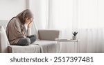 Depression concept. Upset muslim woman in hijab crying on sofa at home, hiding her face in hands, feeling desperate and lonely, free space