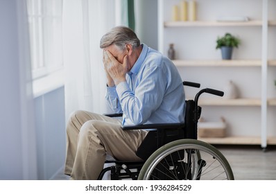 Depression And Loneliness In Disabled Seniors. Elderly Man In Wheelchair Crying Near Window Indoors