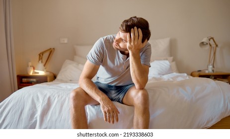 Depression, Mental Health And Sad Man In Stress Feeling Bad, Upset And Depressed Alone In His Home, House Or Hotel Suite. Wake Up, Morning And Frustrated, Unhappy Male In Bedroom Tired With Anxiety