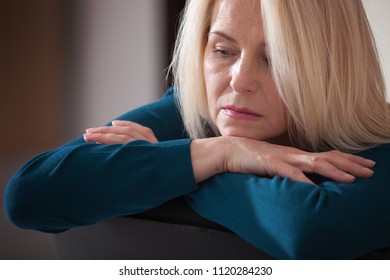 Depression. Middle Aged Woman Barefoot Sitting On The Couch, Hugging Her Head, At Home. The Concept Of Sadness And Loneliness.