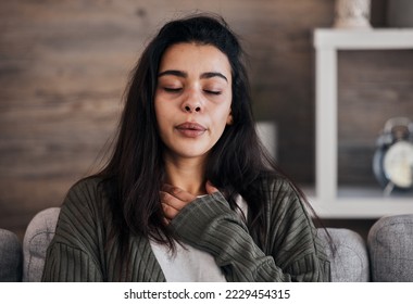 Depression, sad and woman with eyes closed in home thinking of problems. Anxiety, mental health and unhappy, depressed and lonely female on sofa in living room trying to calm down and relax in house.