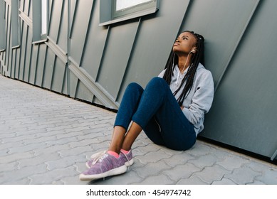 Depression Teen African American Girl Listening To Music And Sitting Lonely Looking Up At Urban Background