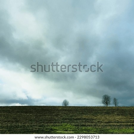 Depressive gloomy sky and the grey green field . Dark cloudy sky on green rice fields before rain storm come.. Flying a drone, Aerial view over agricultural fields where farmers burn fires, Central Eu