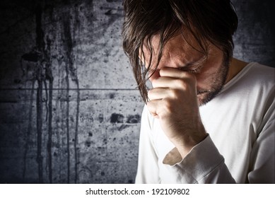 Depressive man crying with hand covering his face, looking upset and showing remorse
