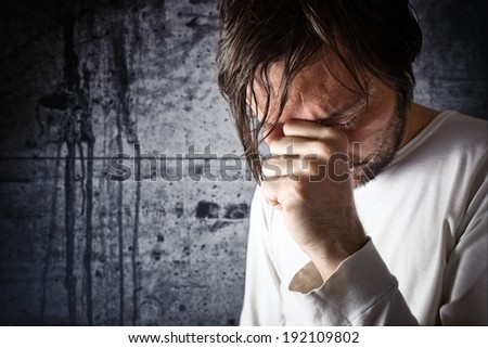Depressive man crying with hand covering his face, looking upset and showing remorse