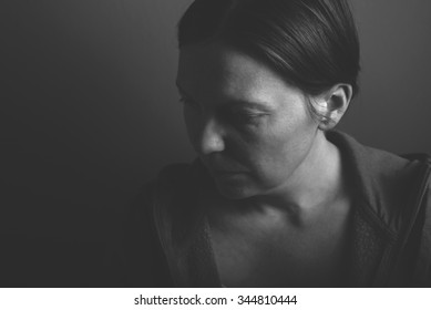 Depressive woman, low key monochromatic portrait of sad adult female in dark room