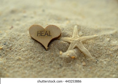 Depth Of Field Heal Text Carved/engraved In Heart Shape Piece Of Wood On Sand Beach With Starfish