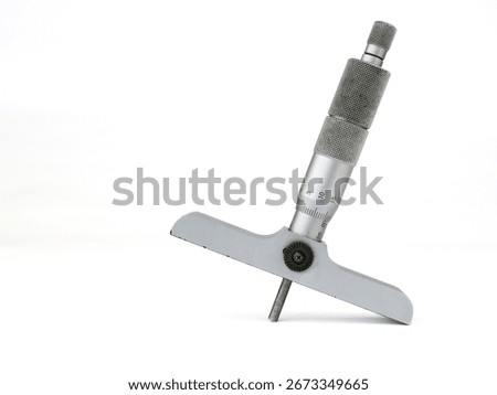 Depth micrometer on a white background. The silver and metallic gray precision measuring tool is shown at an angle, highlighting its scale and design.