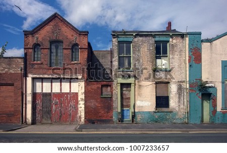 derelict houses and abandoned commercial property on a residential street with boarded up windows and decaying crumbling walls