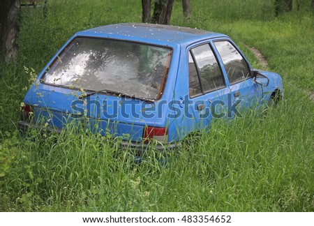 Derelict old car is overgrown with grass