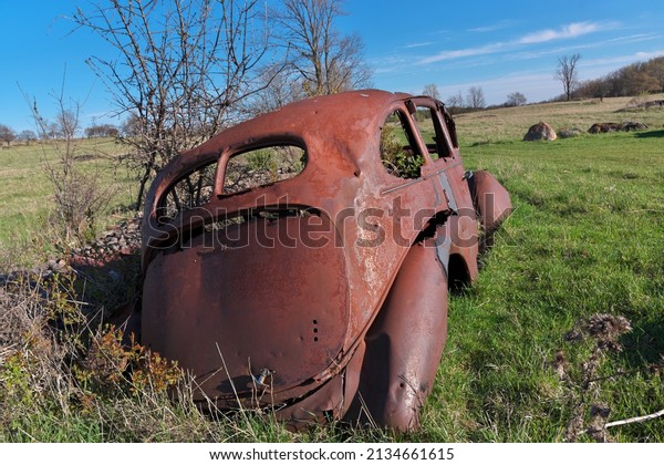 Derelict and rusty antique Vintage Car in a Farm\
Field on a Sunny Day