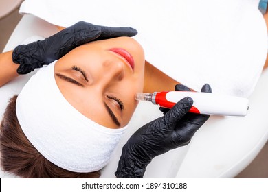 Dermapen apparatus in the hands of a beautician. New skin rejuvenation procedure. Fractional mesotherapy procedure. Cosmetic device.