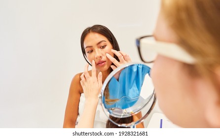 A dermatologist or beautician examines a woman's facial skin before a facelift