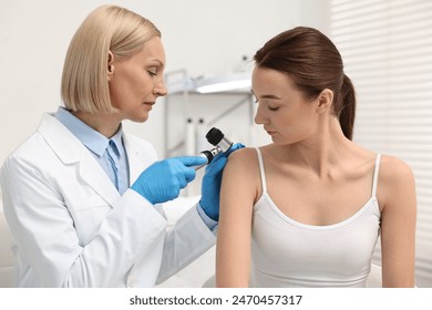 Dermatologist with dermatoscope examining patient in clinic - Powered by Shutterstock