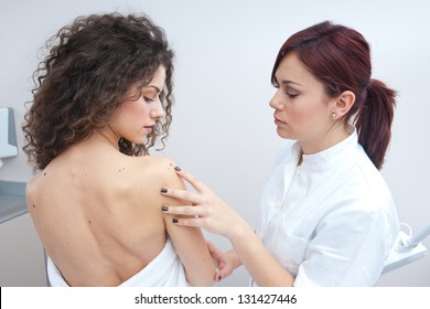 Dermatologist Doctor Inspecting Woman Skin For Moles And Melanoma