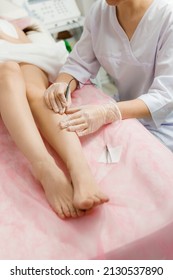 Dermatologist doing hair removal treatment on patient's leg with electrolysis. Depilation and beauty concept, hands doing electro-epilation. Doctor working in cosmetic medical cabinet.