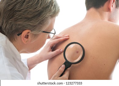 Dermatologist examines a mole of male patient