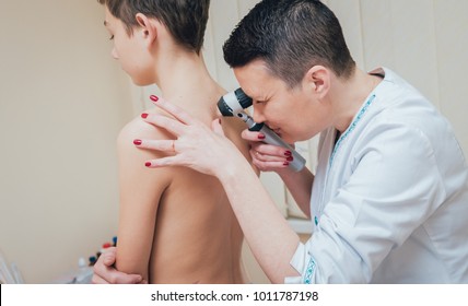 Dermatologist examines patient birthmark with dermatoscope. Medical equipment.
