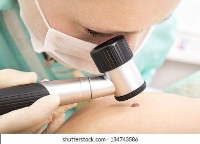 Dermatologist examines patient birthmark with dermatoscope. Mole checkup. Professional dermoscopy - Powered by Shutterstock