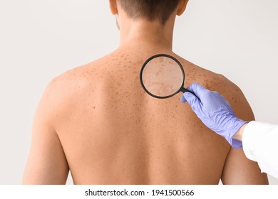 Dermatologist Examining Patient On Light Background