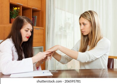 Dermatologist looking at  patient hands at table - Shutterstock ID 206595781