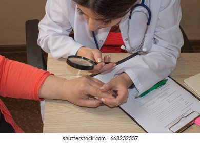 Dermatologist looking at woman's hand through a magnifying glass. Doctor and patient. Medical and Health care concept