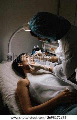 Dermatologist performs precise laser removal of a facial nevus and other benign lesions. Laser dermatologic treatment for nevus and mole removal. Aesthetic laser removal of nevi and benign growths