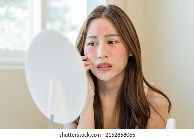 Dermatology, puberty asian young woman, girl looking into mirror, allergy presenting an allergic reaction from cosmetic, red spot or  rash on face. Beauty care from skin problem by medical treatment. - Shutterstock ID 2152858065