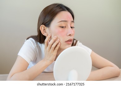 Dermatology, puberty asian young woman, girl looking into mirror, allergy presenting an allergic reaction from cosmetic, red spot or  rash on face. Beauty care from skin problem by medical treatment. - Shutterstock ID 2167177325