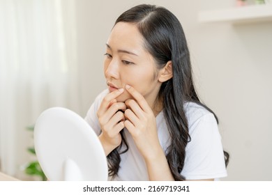 Dermatology, puberty asian young woman, girl looking into mirror, allergic when facial dirty and cosmetic, show squeezing pimple spot on her face. Beauty care from skin problem by acne treatment.