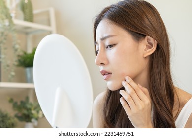 Dermatology, puberty asian young woman, girl looking into mirror, allergy when wear mask and cosmetic, show squeezing pimple spot for removing from face.Beauty care from skin problem by acne treatment - Shutterstock ID 2231469751