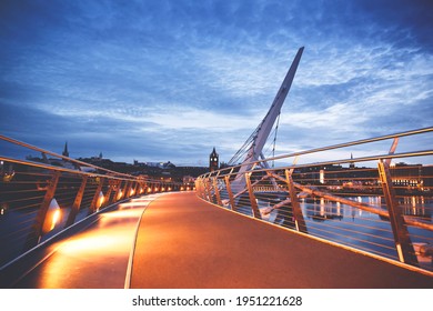 Derry, Ireland. Illuminated Peace bridge in Derry Londonderry, City of Culture, in Northern Ireland with city center at the background. Night cloudy sky with reflection in the river at the dusk.