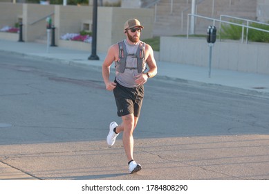 Des Moines, IA / United States Of America - July 11th, 2020 : A Man Runs Wearing A Hydration Backpack Down The Middle Of A Street During A Socially Distanced 5k Run / Walk, Early In The Morning.  