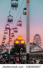  Des Moines, Iowa / United States - August 10, 2018: Sunset Scene Of Crowds Of People, A Ferris Wheel, Ye Old Mill And The Sky Glider At The Iowa State Fair, Des Moines, Iowa, USA. 