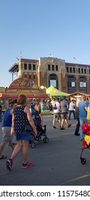 Des Moines, Iowa / USA - 8/04/2018: State Fair With Food Trucks, People, And Grandstand With American Flags And Baby Stroller