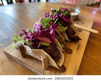 
Description
A visually stunning platter of three gourmet street tacos is presented on a rustic wooden board.