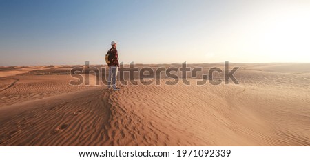Desert adventure. Young man with backpack walking on sand dune. The ghost town of Al-Madam near Dubai, United Arab Emirates. idea and concept of success and achieving a goal