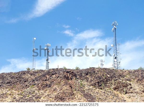 Desert Antenna Repeater Towers, \
Communications Towers. Blue sky with clouds in\
background.