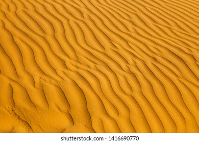 Desert as a background. Beautiful structure of sand dunes on a sunny summer day. Desert at sunset close-up, top view. Waves of sand in the desert